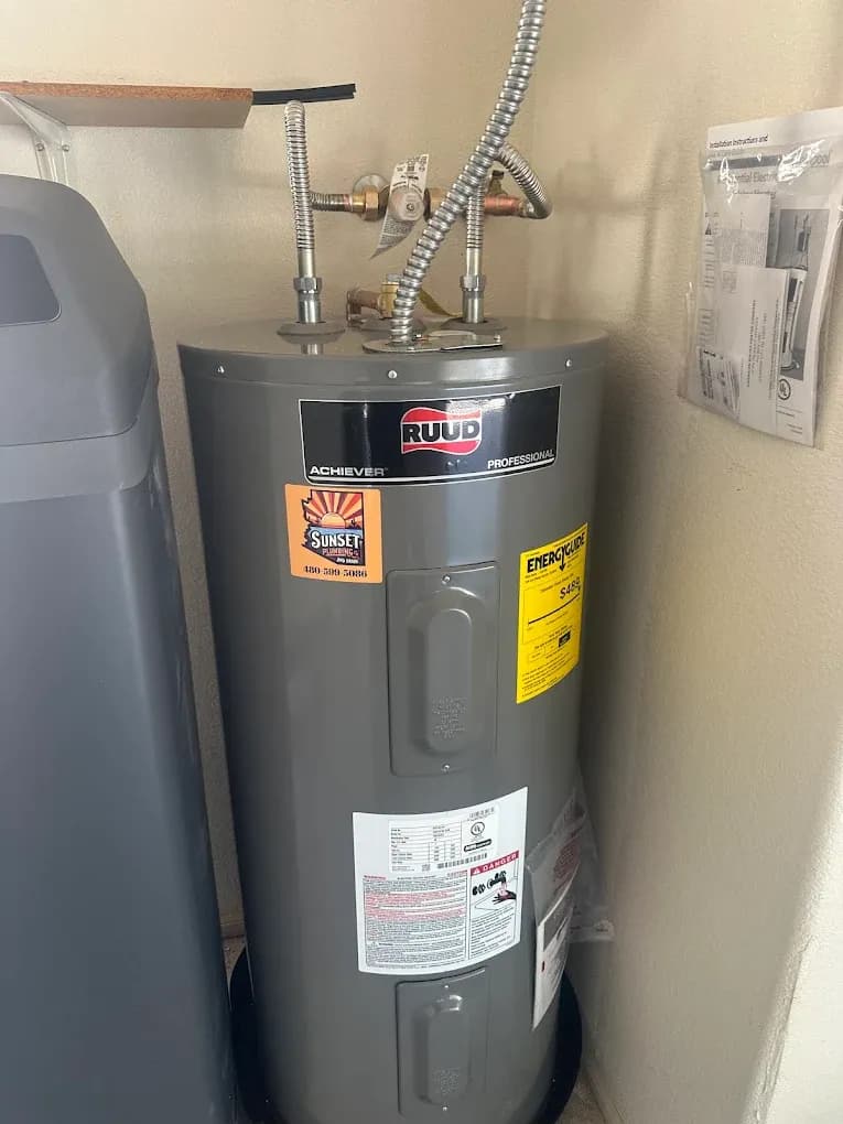 RUUD water heater with a Sunset Plumbing sticker beside a water softener